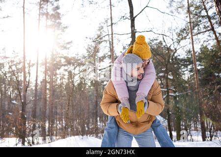 Glückliche Frau Huckepack auf Freund im Winter-Outfit im Park Stockfoto