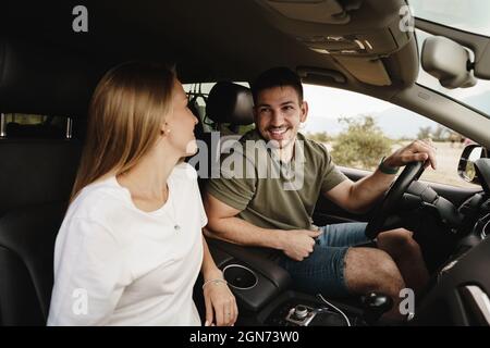 Schönes junges Paar, das auf Beifahrersitzen sitzt und ein Auto fährt Stockfoto