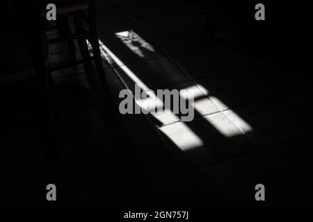 Lichteinfall durch Fenster auf Steinboden mit langen schönen scharfen Schatten Dunkle Zimmer Konzept Bild Stockfoto