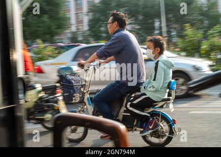 Ein Chinese bringt seinen Sohn am frühen Morgen in Peking, China, auf einem Fahrrad zur Schule. 23-Sep-2021 Stockfoto