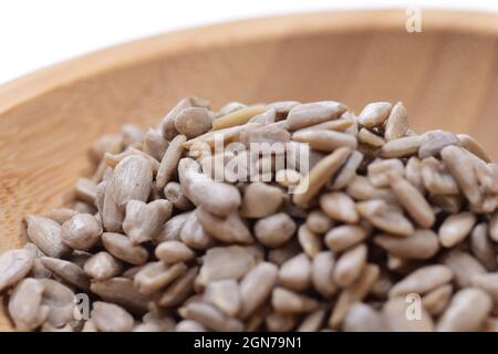 Geschälte Sonnenblumenkerne auf einer Holzschale vor weißem Hintergrund. Essen. Stockfoto