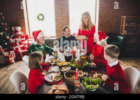 Fotoporträt der Mutter halten köstliche festliche Kuchen lächelnde Familie am Tisch sitzen Stockfoto