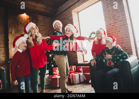 Fotoportrait von Vater, der mit Tochter bei Großeltern spielt, die an weihnachten Champagner trinken und gemeinsam lachen Stockfoto