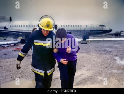 Feuerwehrleute und Sanitäter, die während einer Schulung und Koordinationsübung am Flughafen Manchester Freiwillige mit simulierten Verletzungen besuchen. Stockfoto