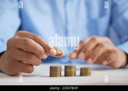 Man's Hand Putting Stapel von Münzen Stockfoto