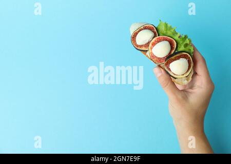 Weibliche Hand hält Bruschetta mit Feige auf blauem Hintergrund Stockfoto