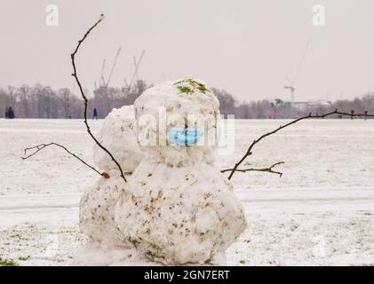 Ein Schneemann mit einer schützenden Gesichtsmaske während der Coronavirus-Pandemie an einem Tag starken Schnees im Hyde Park. London, Großbritannien 24. Januar 2021. Stockfoto