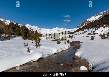 Panorama mit viel Schnee auf Lukmanier im Tessin, auf die Schweizer Alpen und ein romantischer Bach durch die Landschaft. Niemand drinnen Stockfoto