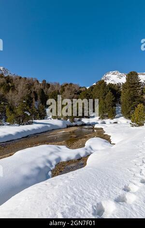 Panorama mit viel Schnee auf Lukmanier im Tessin, auf die Schweizer Alpen und ein romantischer Bach durch die Landschaft. Niemand drinnen Stockfoto