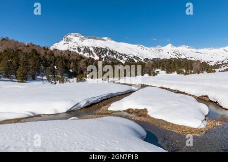 Panorama mit viel Schnee auf Lukmanier im Tessin, auf die Schweizer Alpen und ein romantischer Bach durch die Landschaft. Niemand drinnen Stockfoto