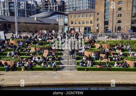 Menschen, die auf den Stufen neben dem Regent's Park am Granary Square in King's Cross sitzen. London, Großbritannien, 2021. Stockfoto