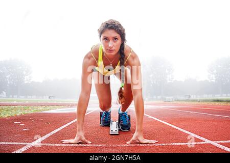 Junge Sportlerin auf den Startblöcken im Nebel Stockfoto