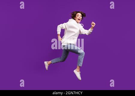 Full-Size-Profil Seitenfoto der jungen guten Laune Mädchen läuft in der Luft unbeschwert freuen isoliert auf lila Farbe Hintergrund Stockfoto