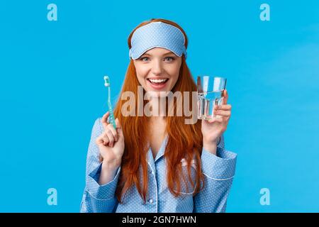 Werbe-, Hygiene- und Personenkonzept. Feminine süße Rotkopfmädchen fühlen sich optimistisch und begeistert den Starttag richtig an, Trinkwasser, Glas und Stockfoto