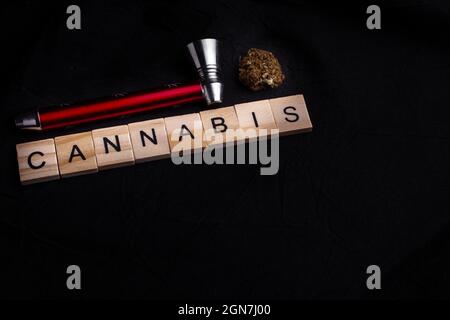 Nahaufnahme von Cannabis-Knospe mit Pfeife, schwarzem Hintergrund und Cannabis-Text. Legalisierung von Cannabis. Stockfoto