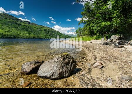 Entlang des West Highland Way in Schottland. Ein kleiner Strand und 2 Felsen am Ufer des Loch Lomond Stockfoto