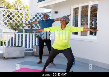 Fokussiertes afroamerikanisches Seniorenpaar, das im Garten Yoga praktiziert Stockfoto