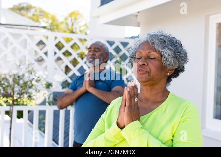 Fokussiertes afroamerikanisches Seniorenpaar, das im Garten Yoga praktiziert Stockfoto