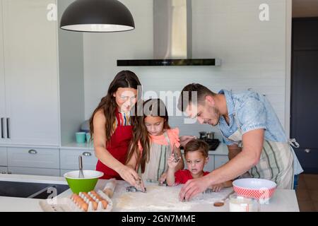 Glückliche kaukasische Familie, die zusammen backt und Kekse in der Küche zubereitet Stockfoto