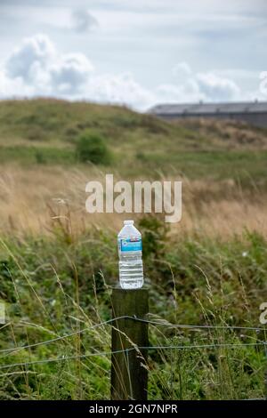 Hurlford, Schottland, Großbritannien. 8. August 2021: Eine Plastikflasche auf einem Holzzaun. Stockfoto