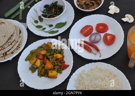 Indisches Essen: Flache Pilzsuppe, saag (Gemüse), Salat, Chapati (indisches Brot), Matar Paneer Mix-Gemüse, Chawal (Reis) und Saft Stockfoto