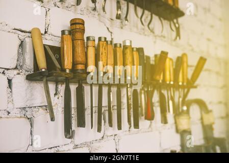 Regal mit Handwerkzeugen auf einem Backsteinwand Hintergrund. Meißel, Sägen und Messer für die Holzbearbeitung. Schreinerei Stockfoto