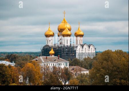 Herbst, christliche Kirche mit goldenen Kuppeln auf dem Hintergrund der Herbstlaub. wolkiger Herbsthimmel. Herbst in Russland Stockfoto