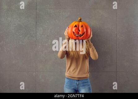 Junge Frau mit geschnitztem Jack-o-Laterne-Kürbis, den sie für die Halloween-Party gemacht hat Stockfoto