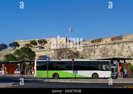 Valletta, Malta Öffentliche Verkehrsmittel Bus am Terminal geparkt. Grüner und weißer Dieselbus an der zentralen Bushaltestelle von Valletta neben der Stadtmauer, an einem sonnigen Tag. Stockfoto