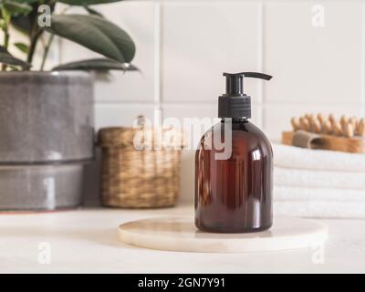 Braune Flasche Mockup für Badeprodukte im Bad, Spa-Shampoo, Duschgel, Flüssigseife auf Marmor Podium und verschiedene Accessoires Vorderansicht. Stockfoto