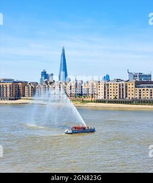 Die Londoner Feuerwehr demonstriert die Kraft ihres Wasserschlauchs aus ihrem Boot Stockfoto