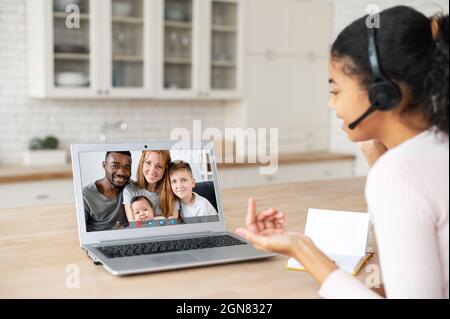 Fröhliche lächelnde afroamerikanische Studentin, die einen Laptop für Videos verwendet, verbindet sich mit der Familie auf der Ferne, junge Frau spricht online Stockfoto