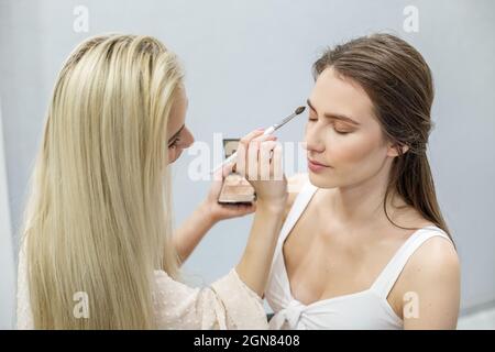 Professionelle Make-up-Künstler macht Make-up. Frau arbeitet in einem Friseursalon. Kleinunternehmen. Arbeitsplatz des Make-up-Künstlers. Stockfoto