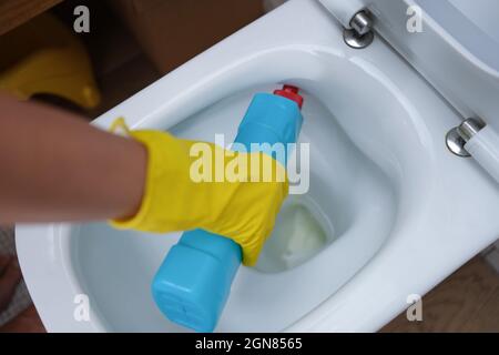 Frau gießt Reinigungsmittel in die Toilettenschüssel aus der Nähe Stockfoto