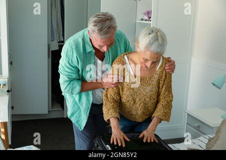Glückliches kaukasisches Seniorenpaar, das Koffer im Schlafzimmer zusammenpackten Stockfoto