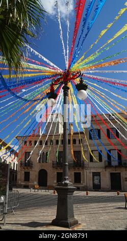 Eine klassische Laterne auf der Straße, die mit bunten Bändern wie einem Riesenrad verziert ist, im traditionellen Dorf Mahon, Menorca, Spanien Stockfoto