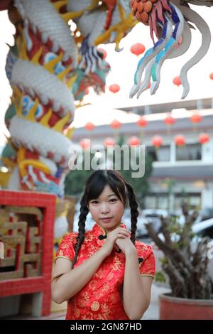 Schönheit Frau tragen rote cheongsam suchen und lächeln auf chinesisch Neues Jahr Stockfoto