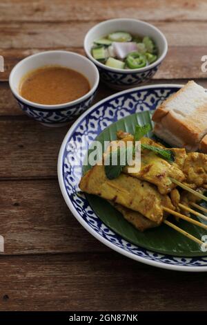 Lokale Thai-Küche Schweinefleisch Satay mit oeanut Dipping Sauce isoliert Im Holzhintergrund Stockfoto