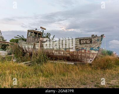 Ein altes, heruntergekommenes Fischerboot, das am Ufer liegt, mit Gras überwuchert, Bisserup, Dänemark, August 8, 2021 Stockfoto