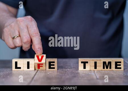 Holzwürfel Abstract in A Life oder Live Time Mans Hand dreht einen Holzblock und ändert die Worte Live to Life Stockfoto