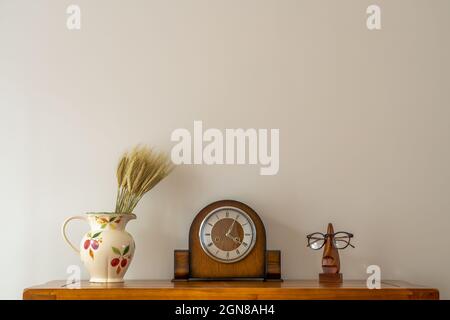 Stillleben der antiken Uhr mit Blumenkrug und optischen Korrektionsgläsern auf dem Ständer Stockfoto