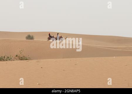 DUBAI, VAE - 4. SEPTEMBER 2018: Am 4. September 2018 reiten Menschen in der Wüste auf Kamelen in der Al Lahbab-Wüste, Dubai, Vereinigte Arabische Emirate Stockfoto