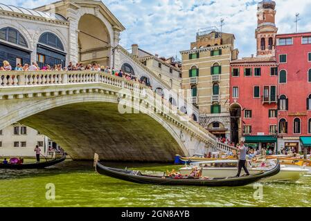 Venedig Venedig Italien Juli 24 2017 Menschen stehen auf der rialtobrücke und blicken hinunter, während eine Gondelbahn-Taxu unter dem Canal Grande vorbeifährt Stockfoto