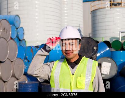 Fabrikarbeiter, der neben Trommeln steht Stockfoto