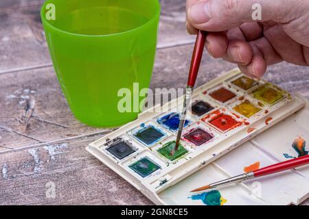 Selektiver Fokus.von einem Künstler-Set von Halbpan-Aquarellfarben in einer Kunststoff-Faltschachtel mit Palette und Pinsel zum Aquarellen Stockfoto