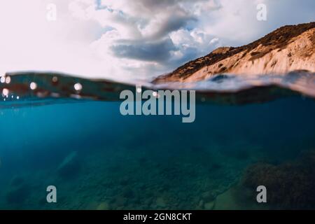 Fifty Fifty Blick mit Küste und Unterwassermeer mit Sonnenstrahlen und transparentem Wasser. Stockfoto