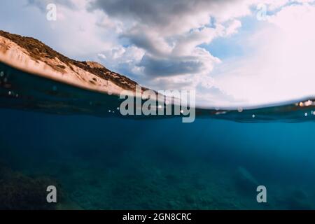 Fifty Fifty Blick mit Küste und Unterwassermeer mit Sonnenstrahlen und transparentem Wasser. Stockfoto