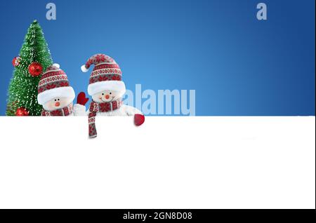 Zwei nette Schneemänner mit leerem Banner auf blauem Hintergrund Stockfoto
