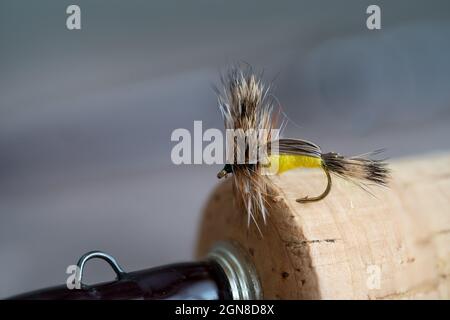 Ausgewählter Fokus Yellow Humpy trockene Fliegenfischen Fliege in den Griff einer Fliegenrute mit Hakenauge eingehakt Stockfoto