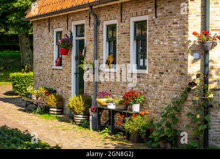 Blick auf die Straße des malerischen holländischen Hauses wunderschön mit Blumen und Clogs dekoriert, in Fort Bourtange, Provinz Groningen Stockfoto
